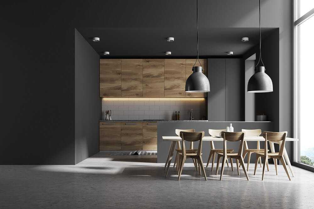 Modern kitchen from a luxury home with polished concrete floors and dark grey walls and light timber cupboards and furniture