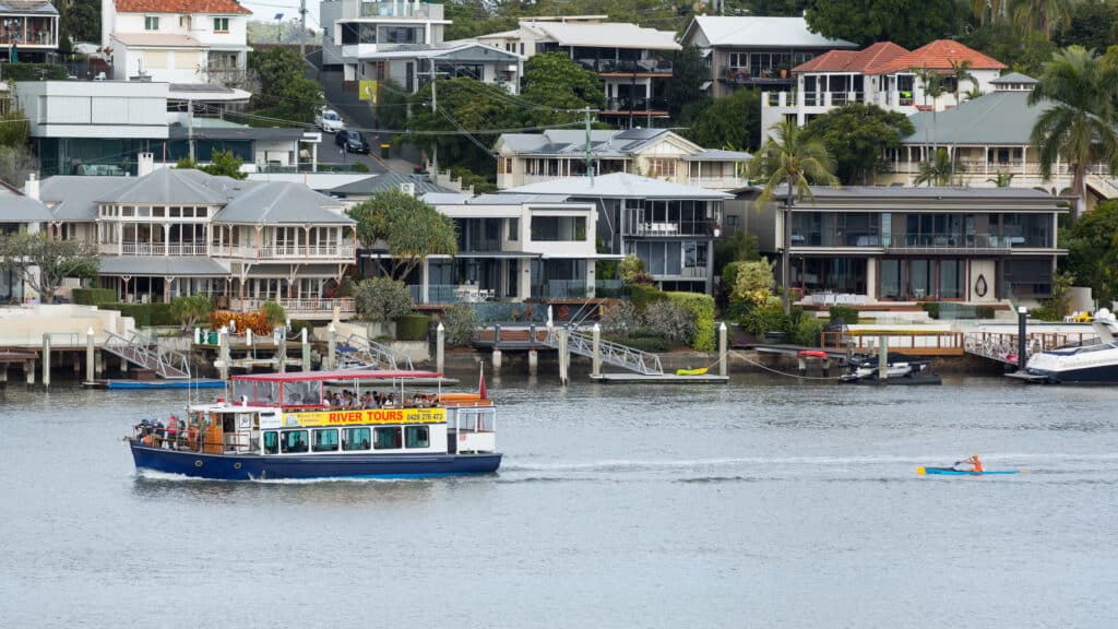 Tourist boat on Brisbane river with houses in the background